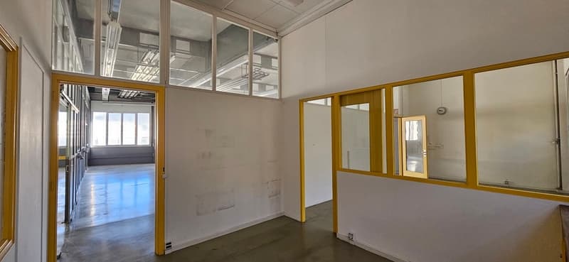 Empty room with white walls, yellow frames, glass windows, and a concrete floor.