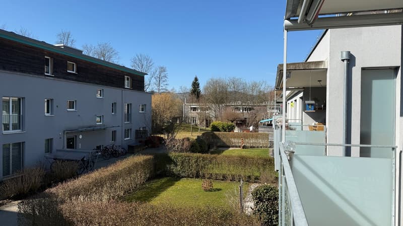 View of the building exterior from the balcony, green hedges, bikes parked