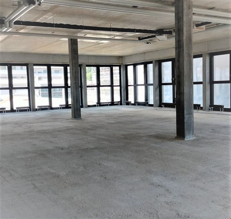 large concrete room, wide windows, ceiling lights, concrete benches