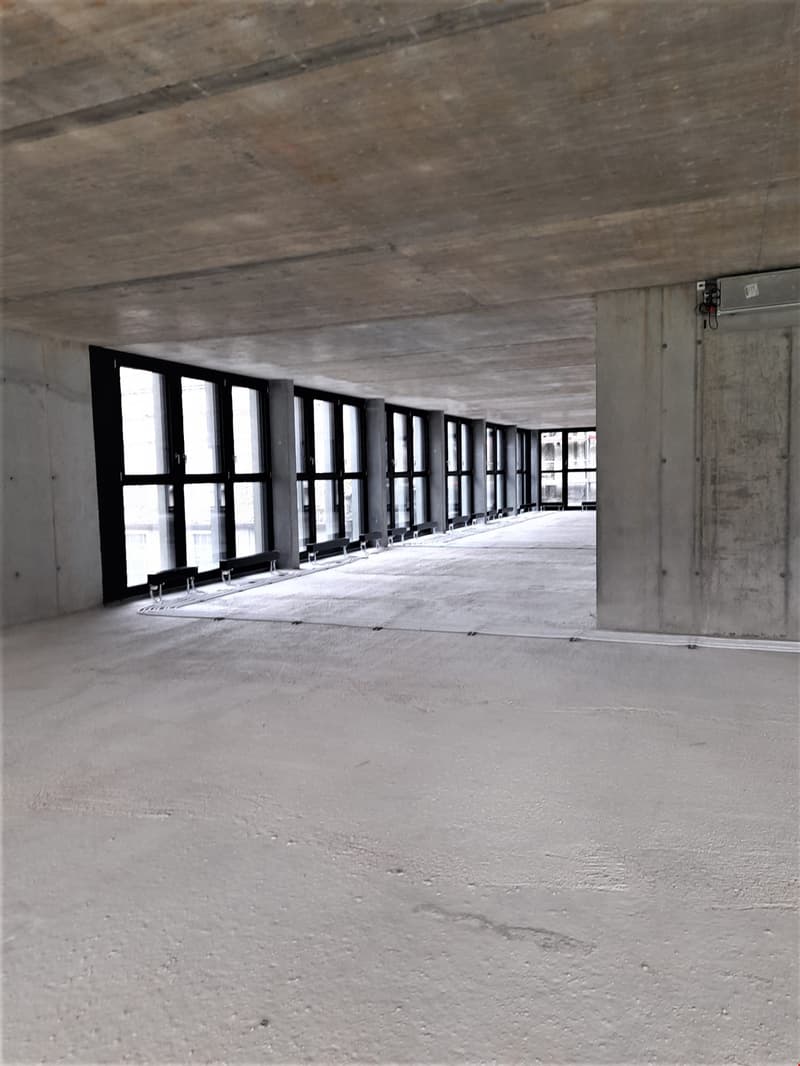 Empty hallway, concrete flooring, large windows, exposed concrete ceiling