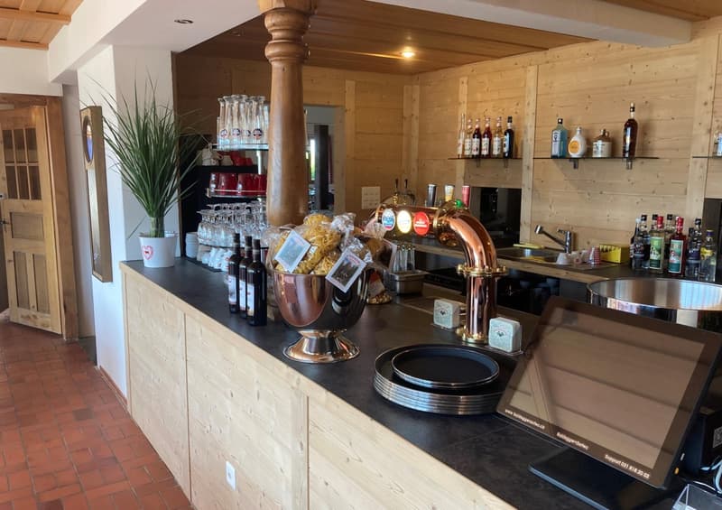 Wooden shelves, wine bottles, wine glasses, copper beer tap, stainless steel bowls, potted plants, red brick floor, wooden door, counter