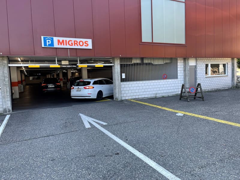 Migros parking lot, multiple cars, arrow painted on ground
