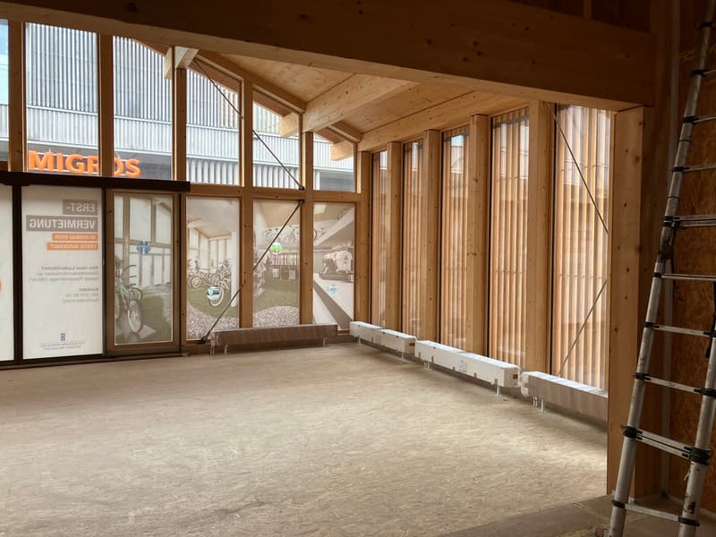 Large open space with wooden beams and walls, concrete floor, and large windows. There is a garage sign visible, indicating this may be a commercial or industrial space.