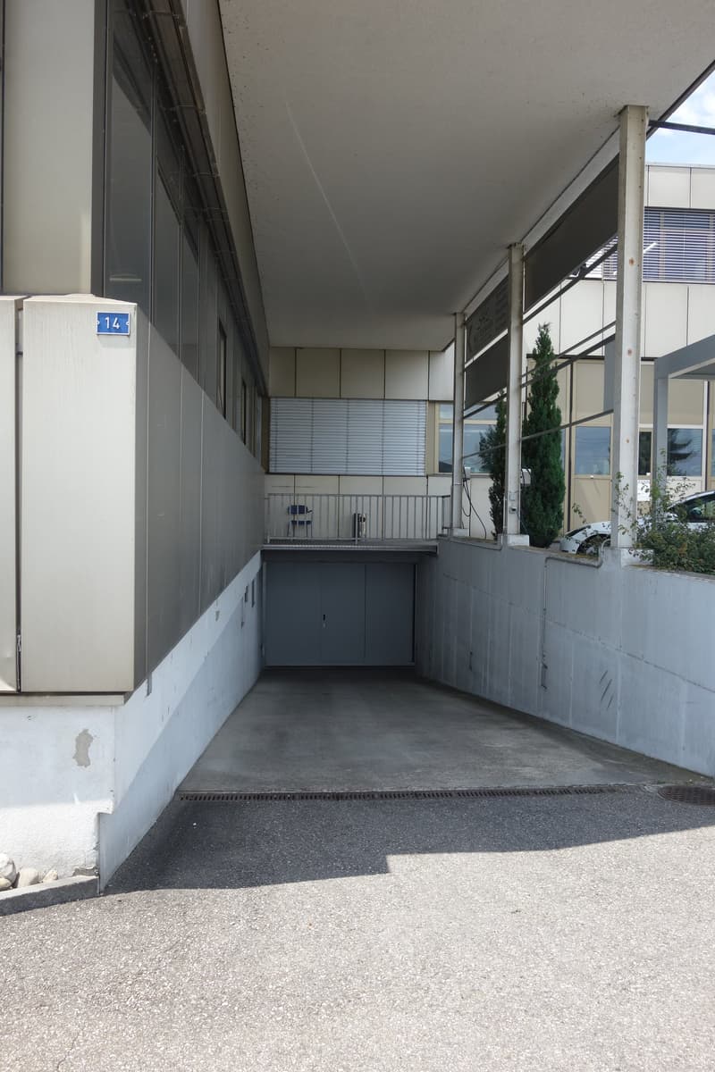 Building: concrete floor, glass window, entrance way with metal railings, garage with metal doors
