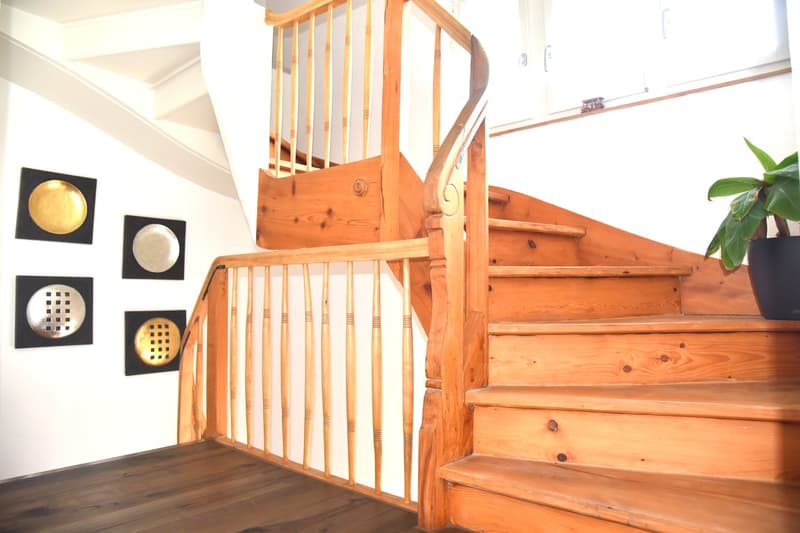 Wooden staircase with handrail, wooden steps, white painted walls, black metal artwork
