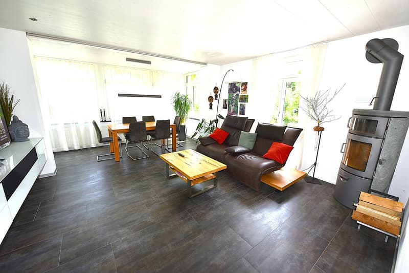 dark tiled floor, modern fireplace, brown sofa, coffee table, 2 chairs, dining table, wooden floor
