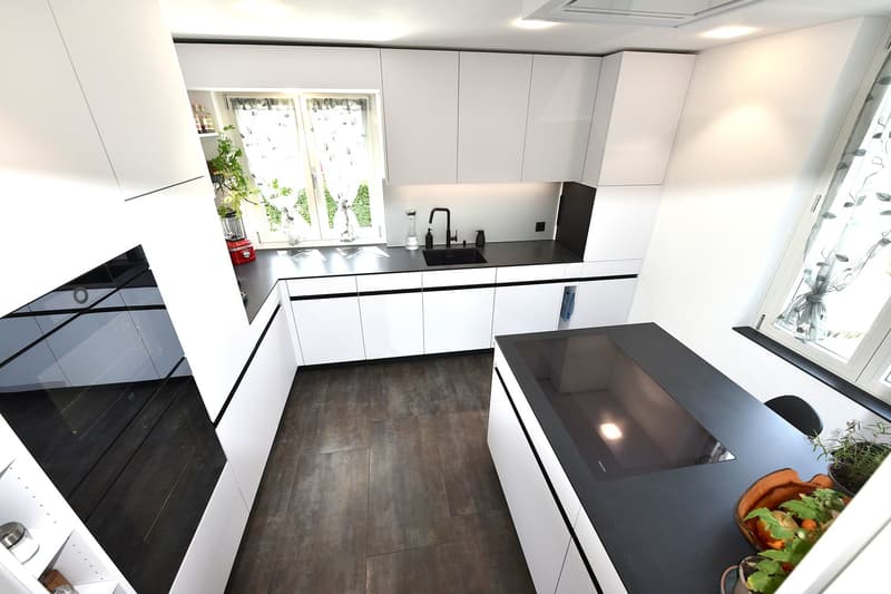 modern kitchen, white cabinets, black countertops, stainless steel appliances, pendant lighting, large windows, potted plants
