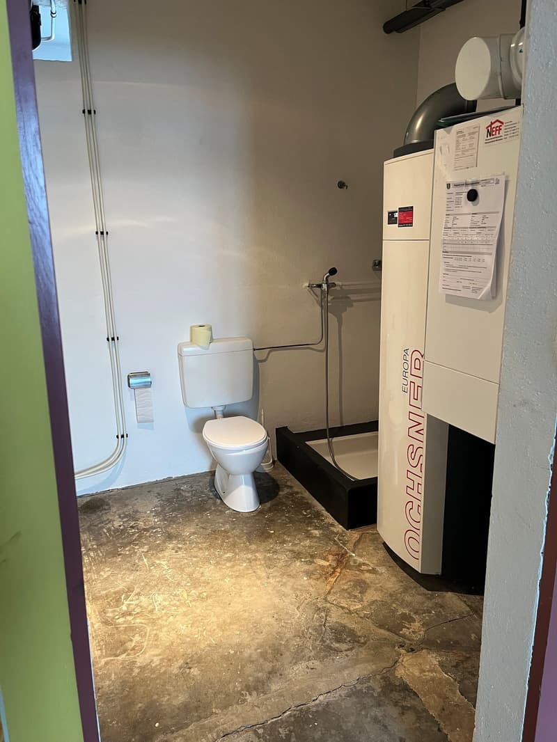 small bathroom with toilet, shower, heater, and pipe installation