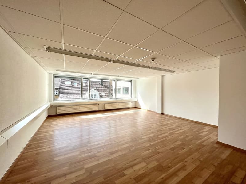 Empty room with wooden floors, windows, and ceiling lighting