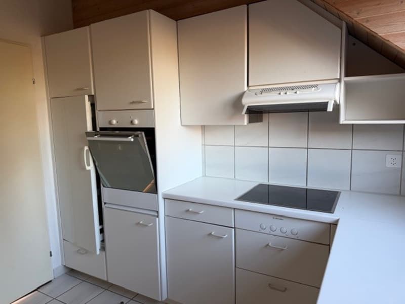 modern kitchen with white cabinets, white tiled walls, black stove, white countertop, white tiled floor, dishwasher, washing machine