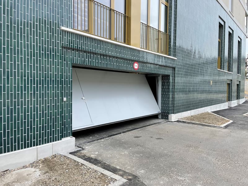 Green tiled exterior, white garage door, overhead balcony, signage