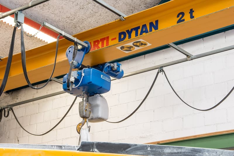 blue hoist with chain, metal framework, yellow overhead support beam