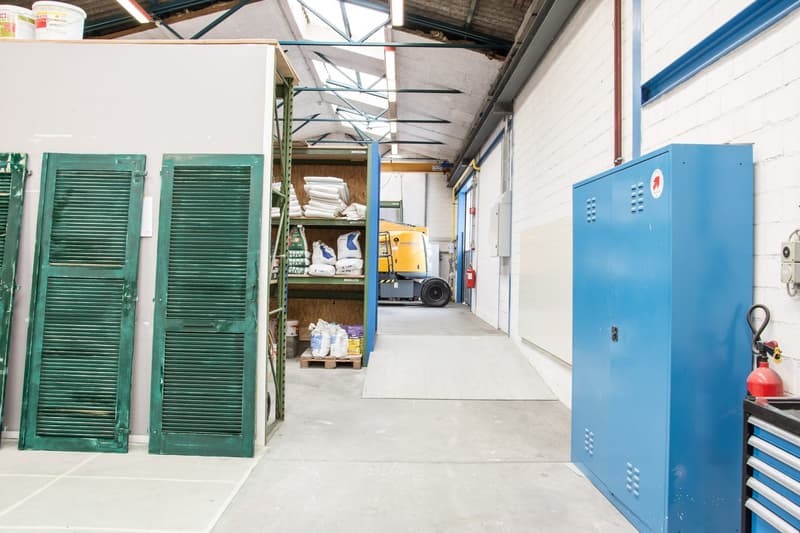 Empty warehouse, green shutters, yellow machinery, white pallet, steel cabinets
