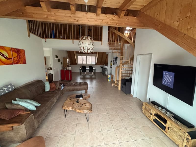 Living room with wooden ceiling, spiral staircase, couch, coffee table, TV, wooden entertainment center