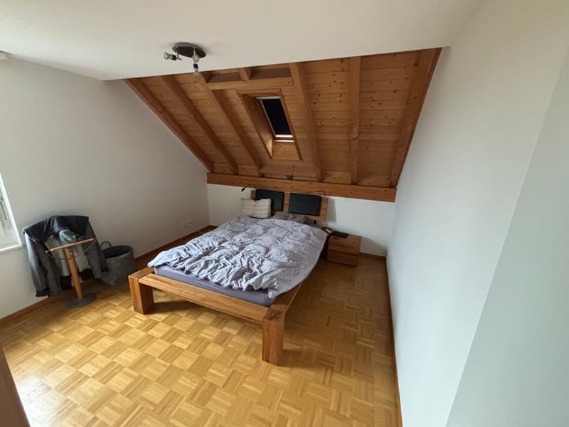 bedroom with wooden bed, wooden floor, wooden ceiling, small window, nightstand, lamp