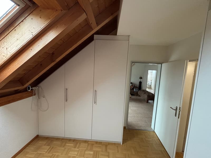 attic room with wooden ceiling, white wardrobe, wooden floor, open door