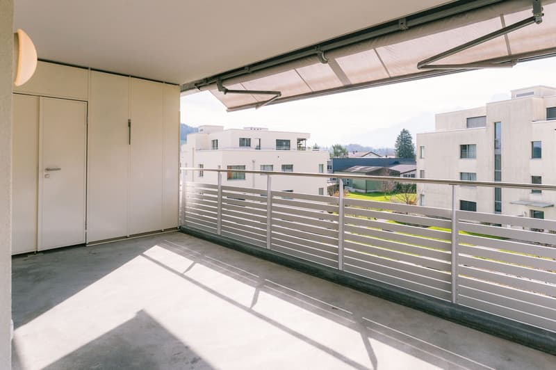 Balcony with white railings, white walls, white ceiling, white door, white storage units, white ceiling lamp