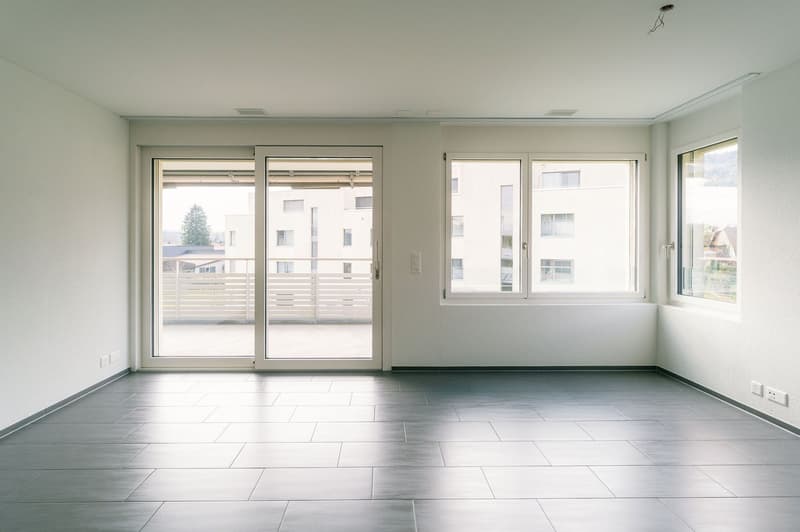 empty room, white walls, tiled floor, sliding glass doors leading to balcony, windows