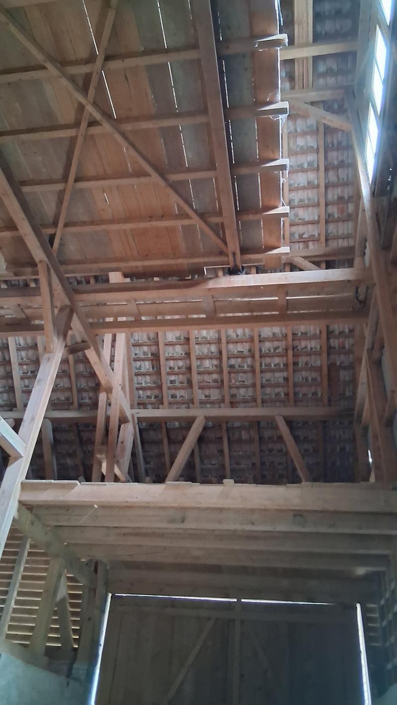 Wooden frame roof, visible beams and cross-beams, multiple wooden shelves