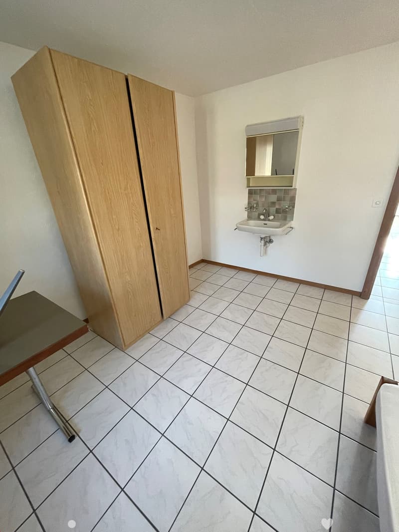 empty room with tiled floor, wooden cabinet, white sink, mirror, power outlet