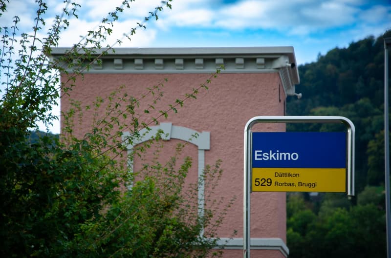 pink building, metal signpost, street sign reading 'Eskimo'