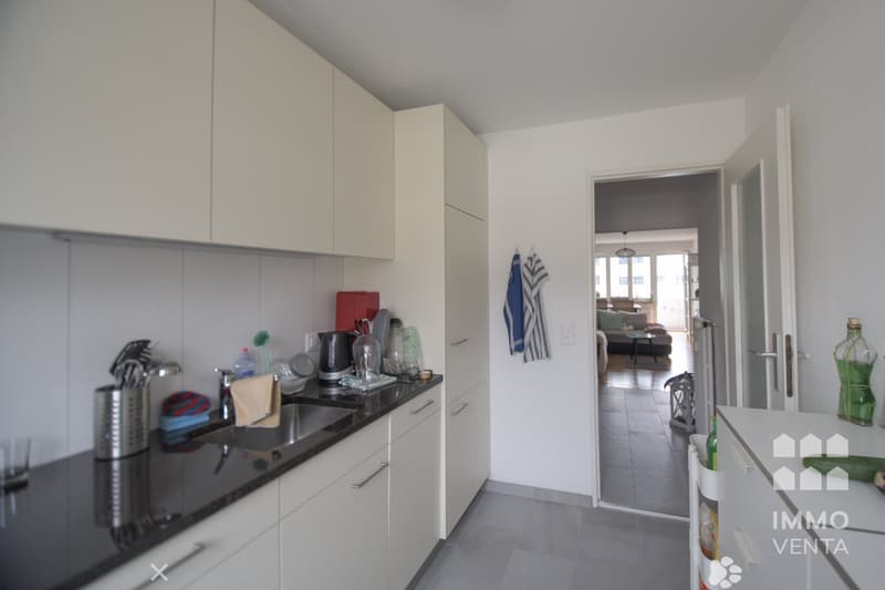 modern kitchen, marble countertop, white cabinets, modern appliances, sink, open door to hallway