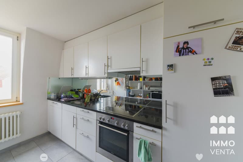 modern kitchen with white cabinets, black countertops, stainless steel appliances, window, radiator