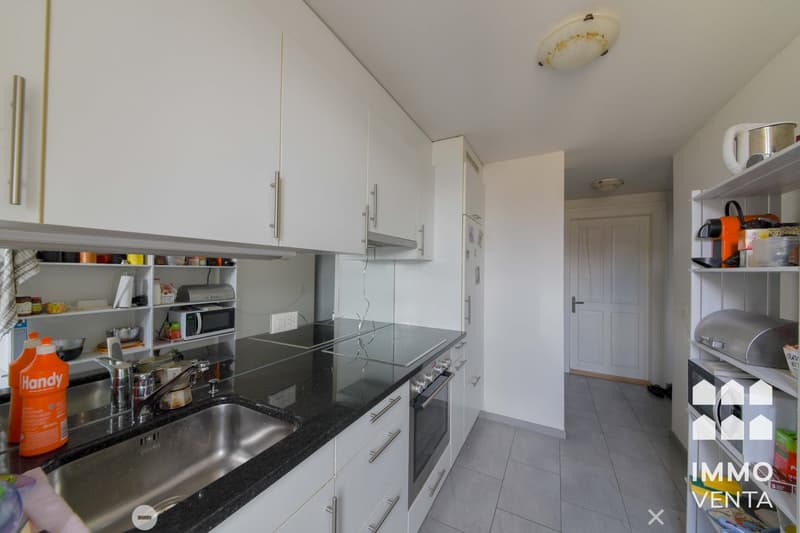 modern kitchen with white cabinets, black granite countertops, stainless steel sink, built-in oven, dishwasher, microwave, and various kitchen utensils