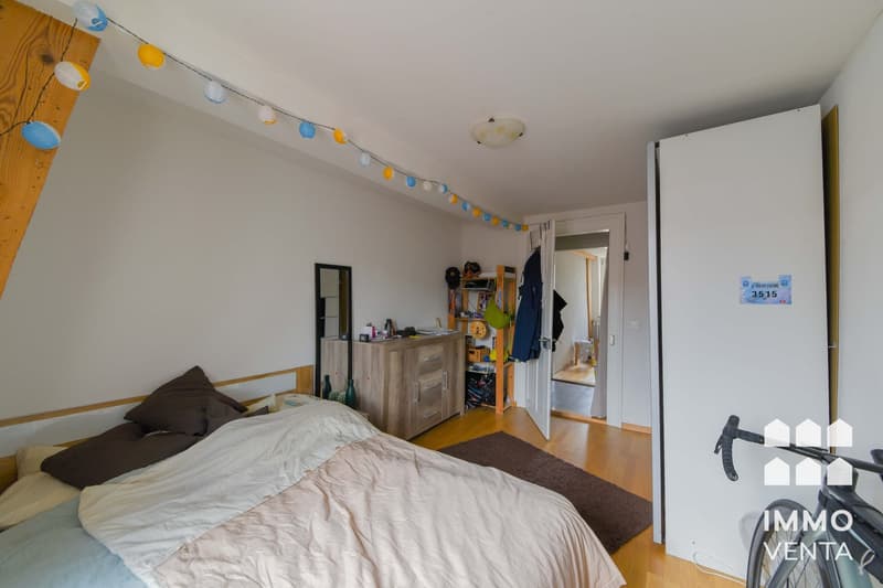 Bedroom with bed, wooden floor, wooden cabinet, mirror, rug, bicycle, string of lanterns