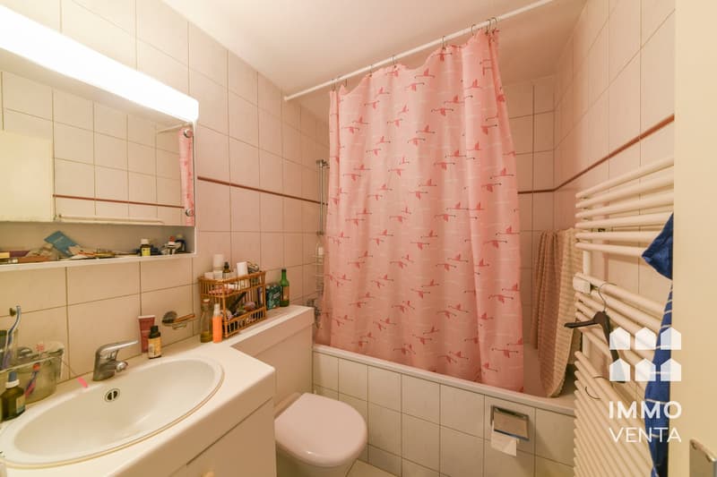 Bathroom with white tiles, white sink, white toilet, pink shower curtain, white towel rack, white radiator