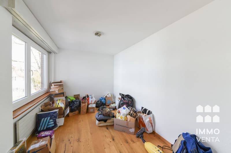 empty room, wooden floor, white walls, large window, boxes and bags scattered around