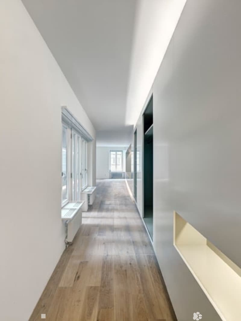 long hallway, wooden floor, white walls, large windows, built-in benches, recessed lighting