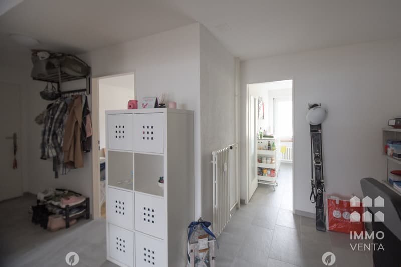 white walls, white floor, white storage unit, white railing, white shelves, skis, bags, clothes