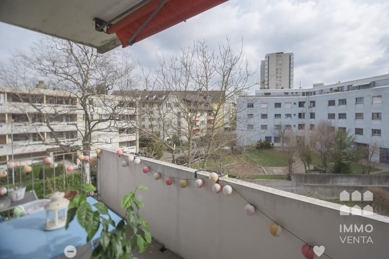 Balcony with a view of the city, string of paper lanterns, a table, and a plant