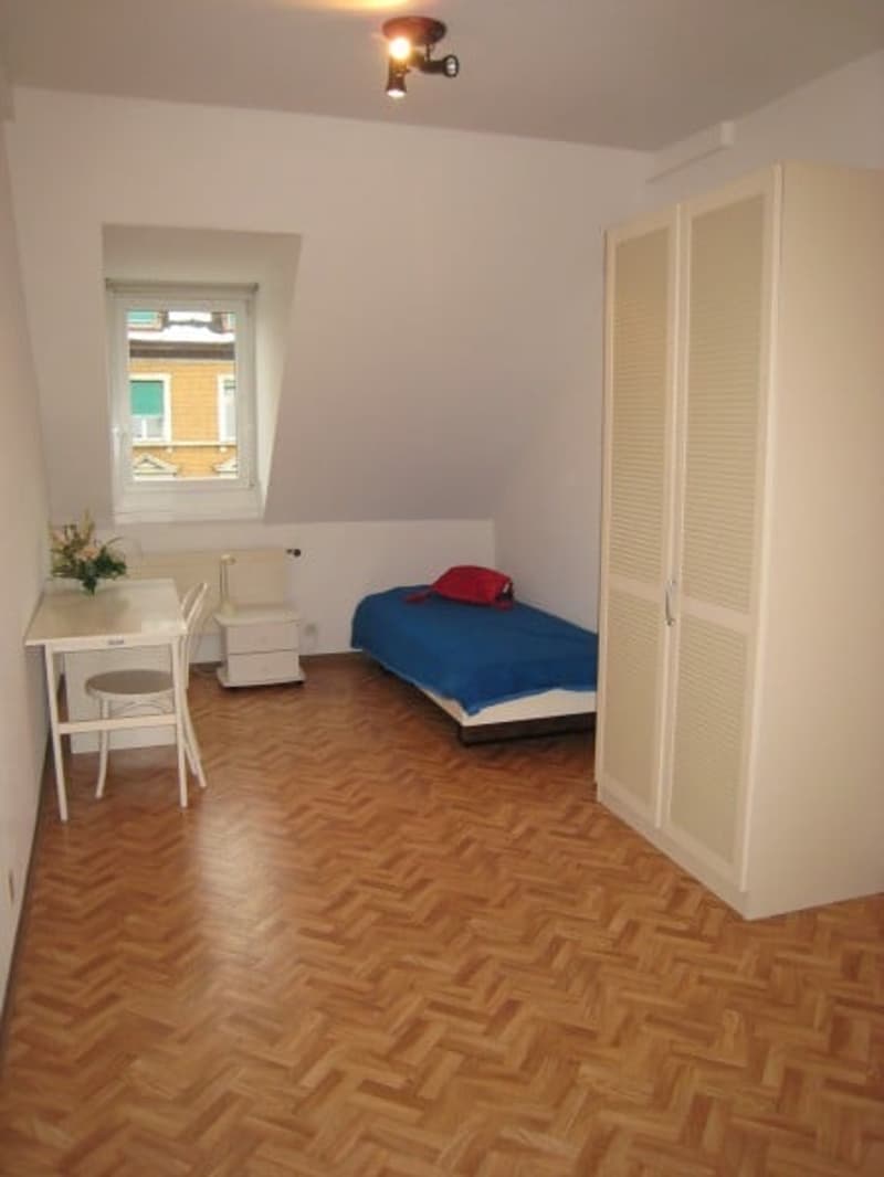 Dachzimmer mit Pult, Bett und Schrank
