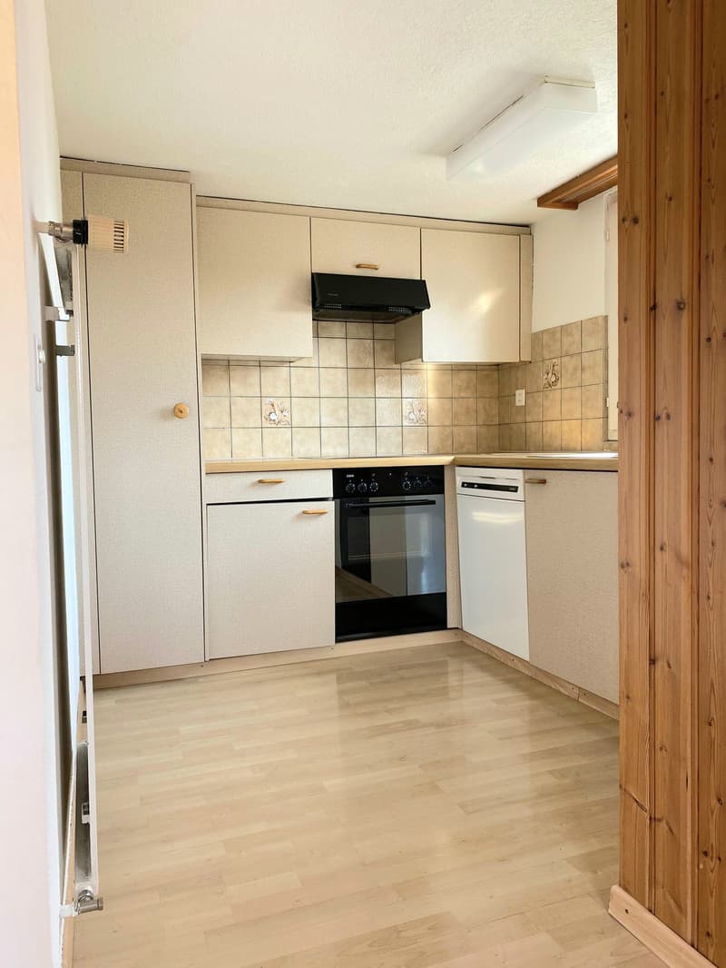 Compact kitchen with white cabinets, tiled backsplash, built-in oven and dishwasher, hardwood flooring