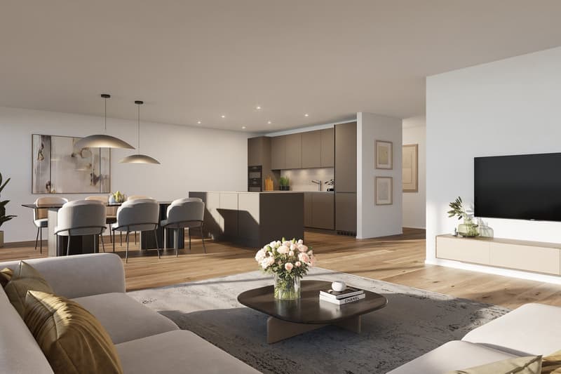 A modern open plan living and dining area, with a contemporary grey sofa, a round coffee table, and an open kitchen with wooden cabinets. There is a dining table with chairs.