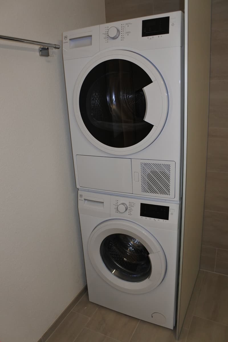 Stacked washing machine and dryer in a corner of a room