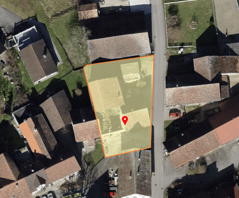 An aerial view of an area in a suburban neighborhood, showing a construction site outlined in orange with a red location pin.
