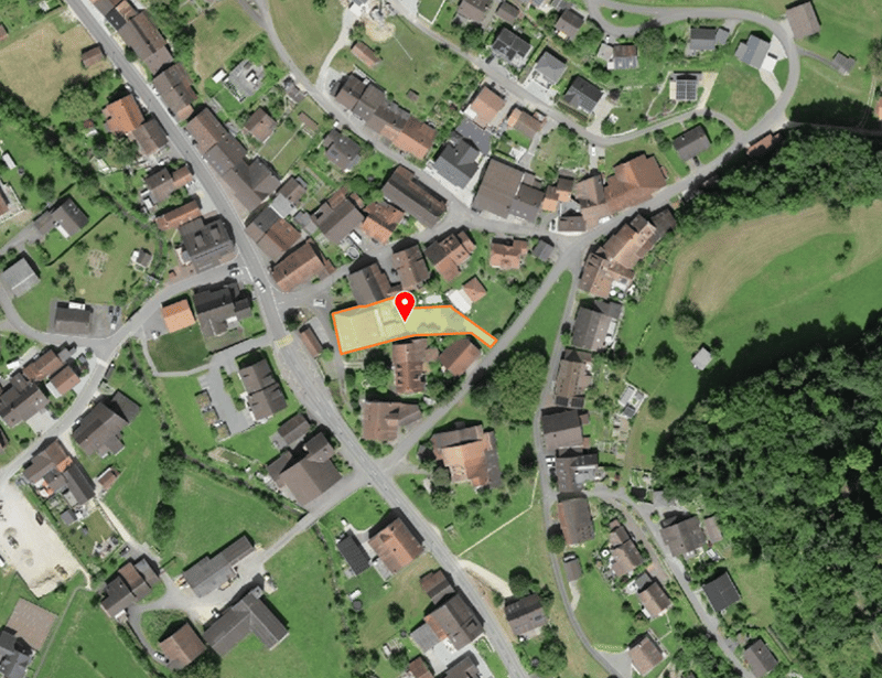 Aerial view of a residential area with several houses, a road, and a green field.
