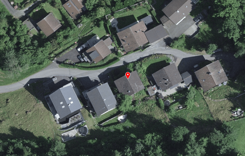 Aerial view of a residential area with several houses, driveways, and parking spaces.