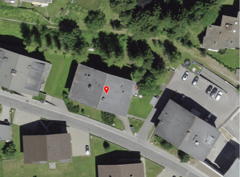 Aerial view of a neighborhood with several houses and a road, marked with a red pin.