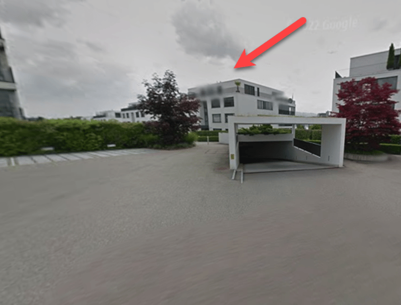 Aerial view of a building with a garage entrance indicated by a red arrow.