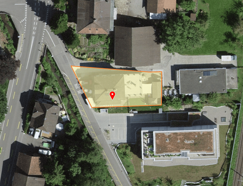 Aerial view of a property with a marked area, surrounded by houses and greenery.