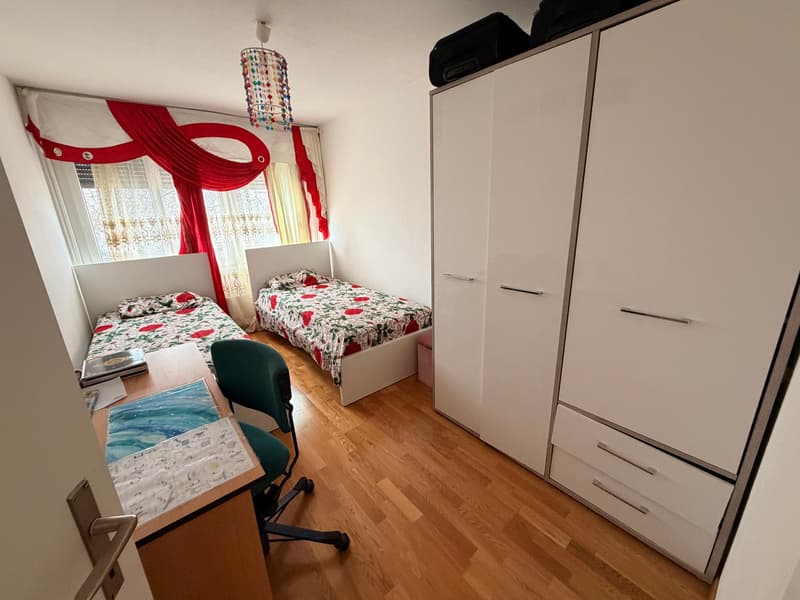 Bedroom with 2 beds, wooden floor, desk, 2 beds, curtains, storage cabinet