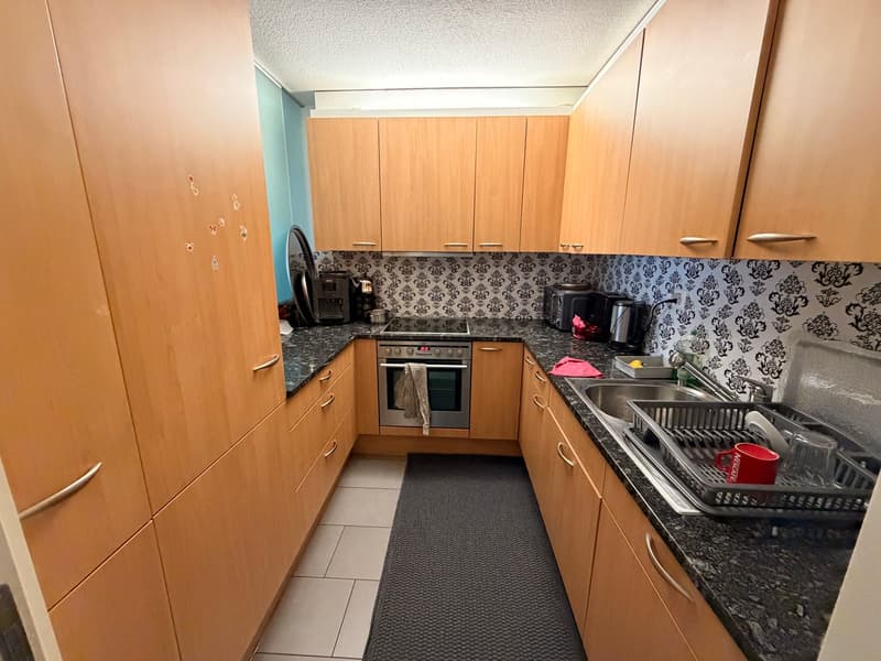 modern kitchen, granite countertops, wooden cabinets, stainless steel appliances, black rug, black countertop