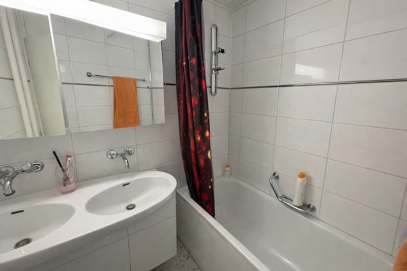 white tiles, bathtub, 2 sinks, mirror, towel, shower curtain