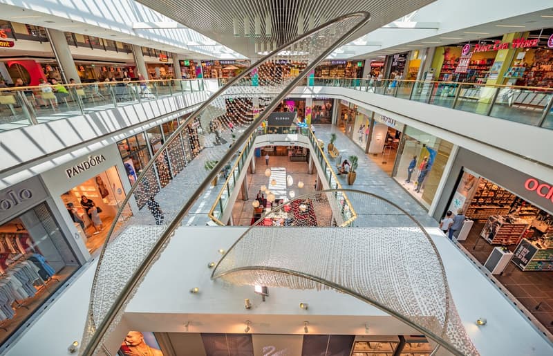 multilevel shopping mall, glass railings, modern art sculpture, many shops, restaurants, cafes