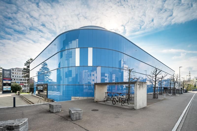 Blue building with large glass windows, bicycles parked outside