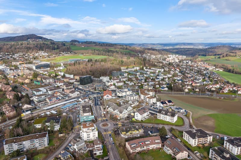 Aerial view of a town with many buildings, roads, and green spaces.